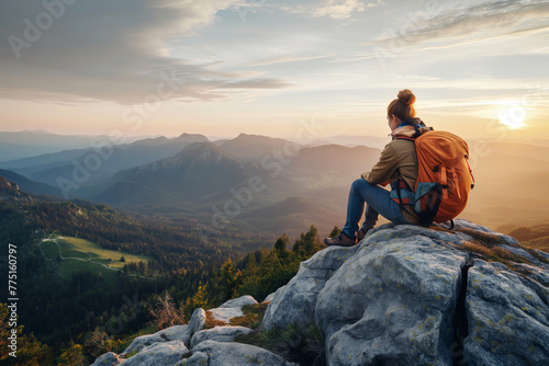A majestic landscape scene of a hiker sitting on a mountain edge, embracing the awe-inspiring view of a sunset over the peaks photo