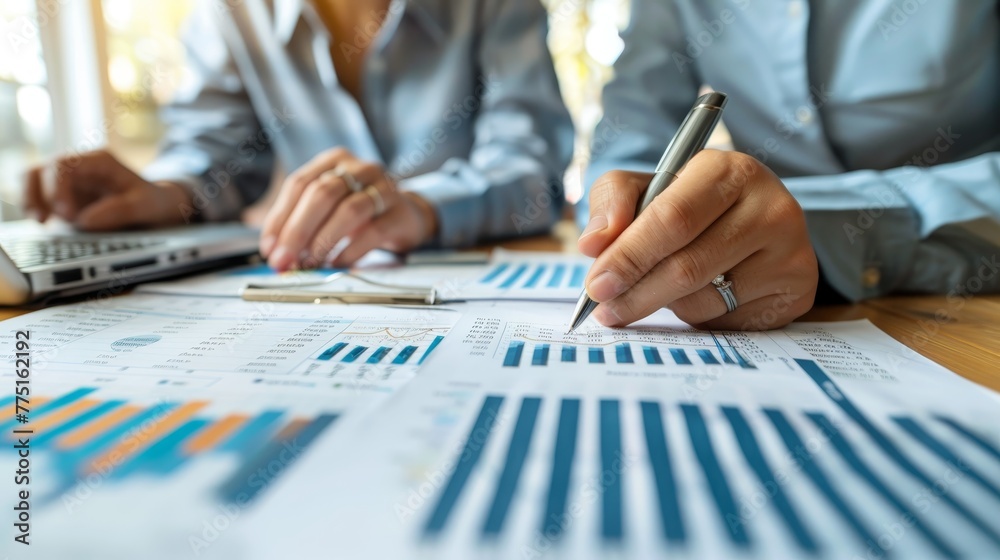 Two people are working on a graph with a pen. One of them is writing on the graph Two people are working on a graph with a pen. One of them is writing on the graph