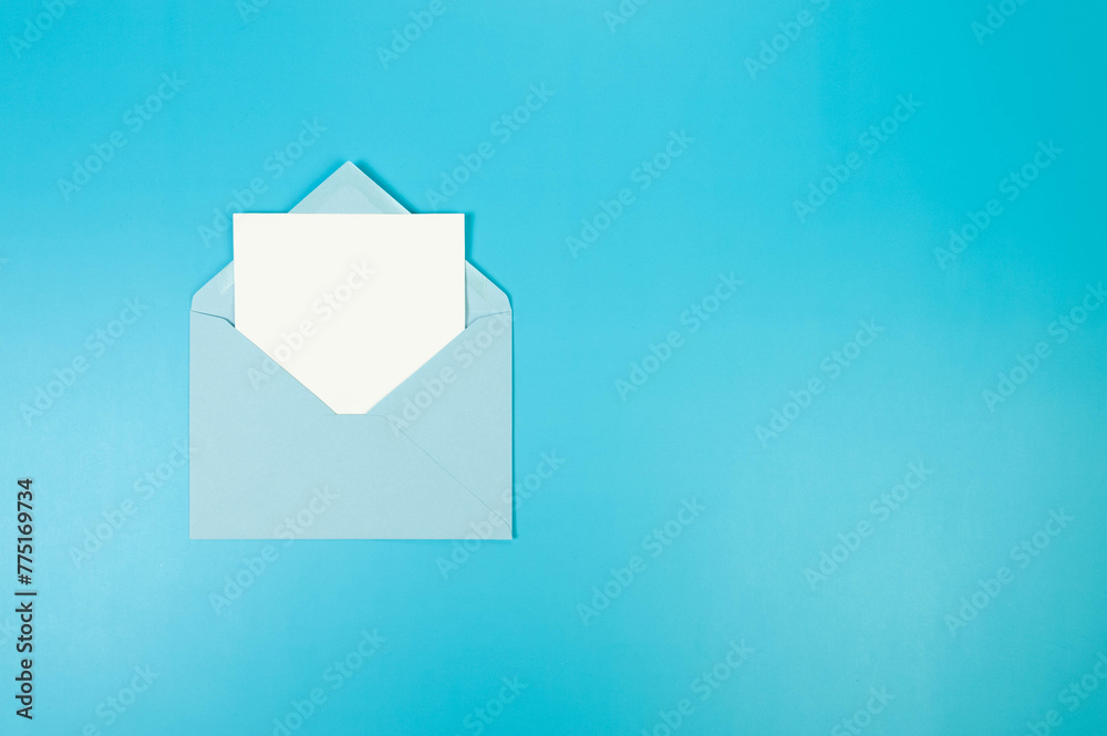 Top view of light blue envelope, white card on blue background. Post flat lay. Copy space. Top view of light blue envelope, white card on blue background. Post flat lay. Copy space.