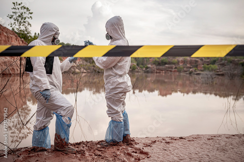 Scientists or biologists wearing protective uniforms working together on water analysis,Environmental engineers inspect water quality in a dangerous area