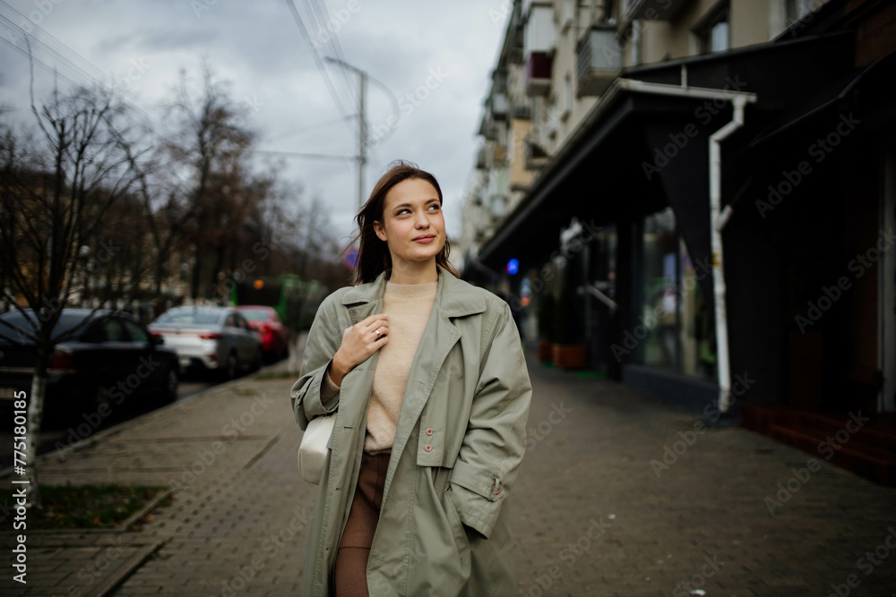beautiful cheerful woman walks around the city in a gray coat in the spring near the shops beautiful cheerful woman walks around the city in a gray coat in the spring near the shops