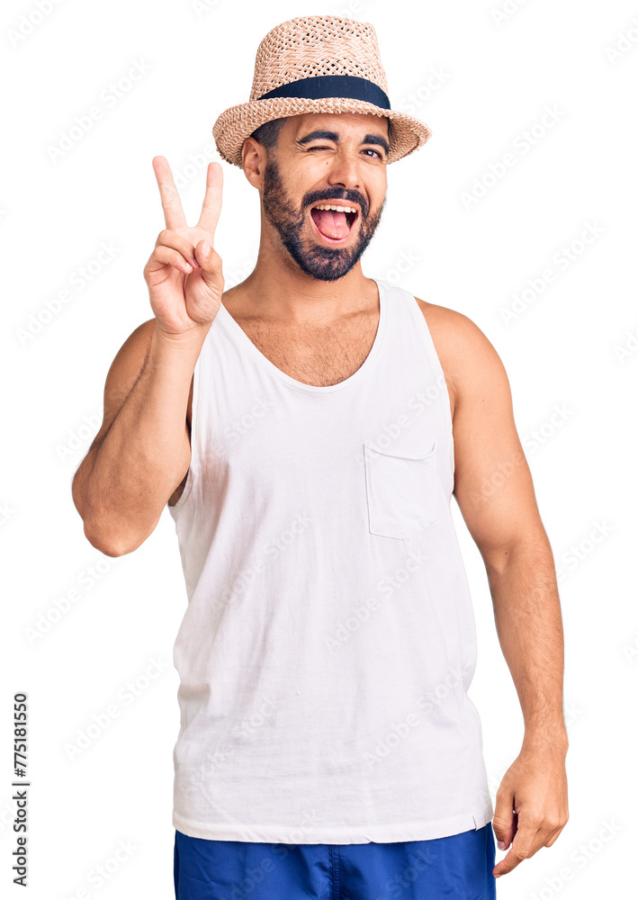 Young hispanic man wearing casual summer hat smiling with happy face winking at the camera doing victory sign. number two. Young hispanic man wearing casual summer hat smiling with happy face winking at the camera doing victory sign. number two.