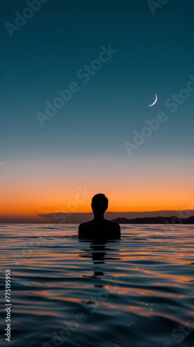 Silhouette of a person in water at sunset with crescent moon