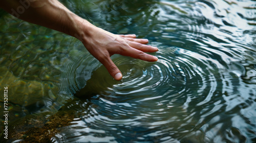 Hand touching water surface creating ripples