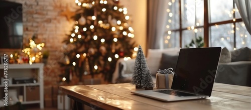 A laptop beside a Christmas tree on a table photo