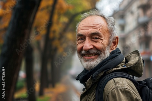 Portrait of an elderly man with a gray beard on the street in autumn