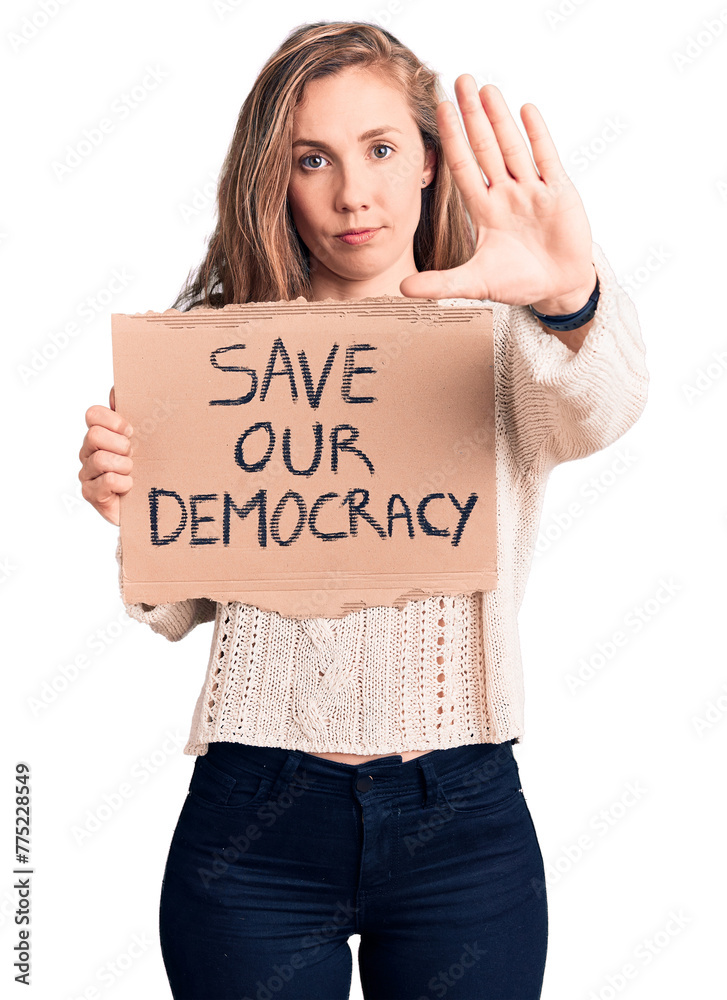 Young beautiful blonde woman holding save our democracy banner with open hand doing stop sign with serious and confident expression, defense gesture Young beautiful blonde woman holding save our democracy banner with open hand doing stop sign with serious and confident expression, defense gesture