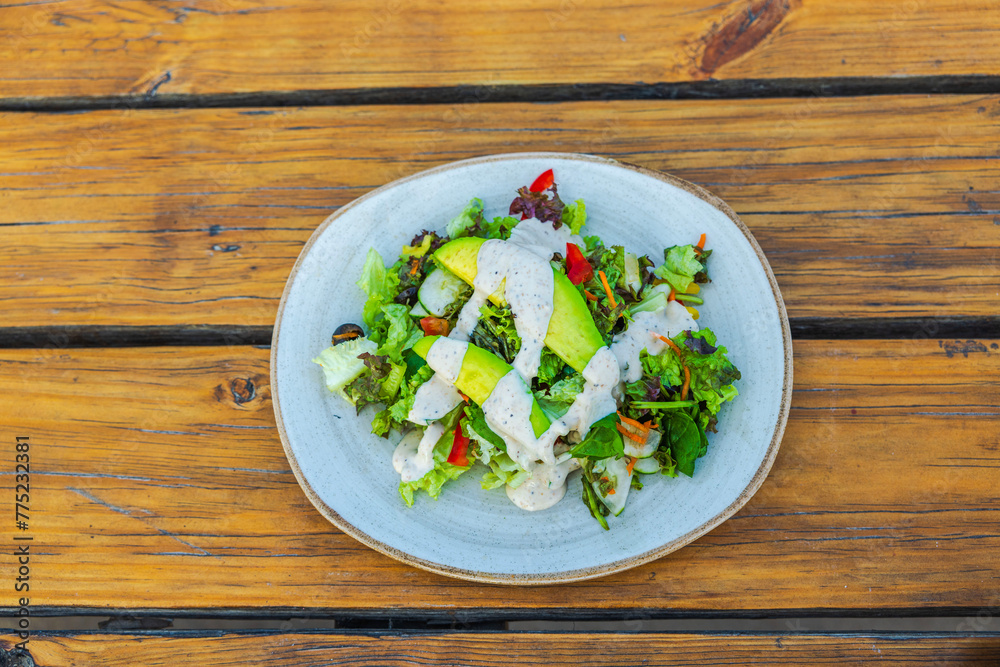 Close-up of a vegetable salad served on a plate in a restaurant. Close-up of a vegetable salad served on a plate in a restaurant.