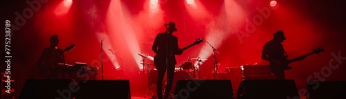 Under the red spotlight, the silhouetted figures of a band merge with the rhythm of music in a live concert photo