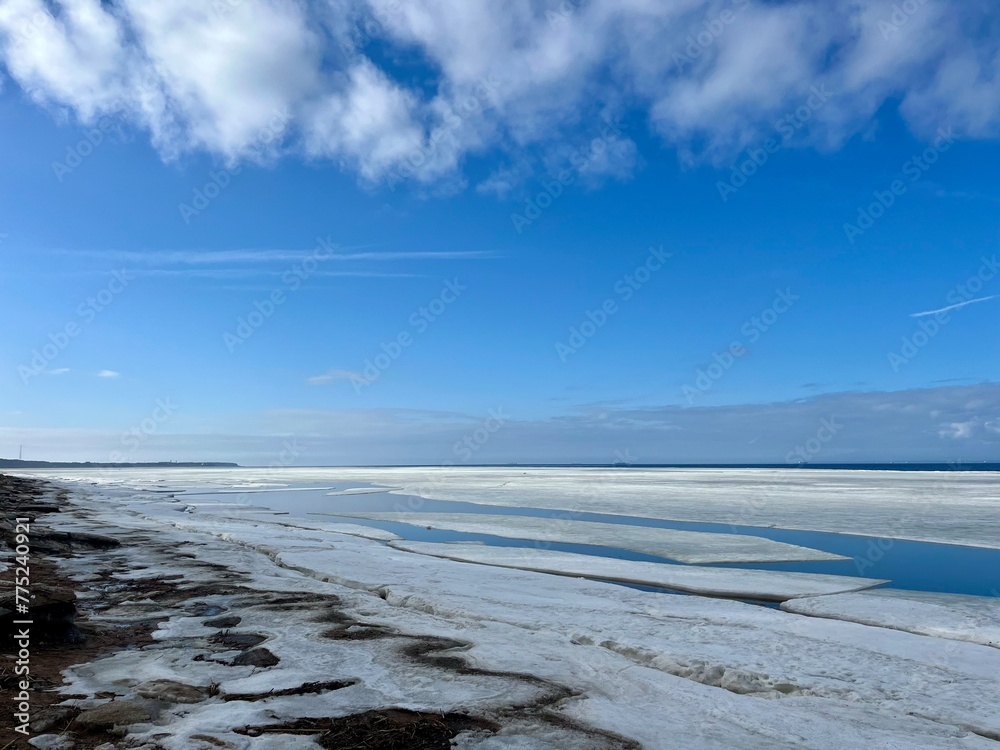 Frozen sea coast, ice at the sea, sea horizon, sky reflection on the water surface, natural colors Frozen sea coast, ice at the sea, sea horizon, sky reflection on the water surface, natural colors