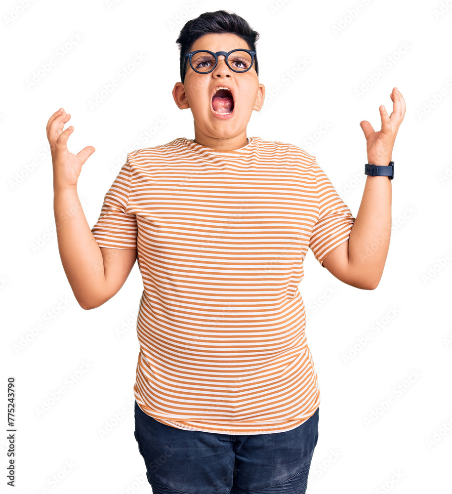 Naklejka premium Little boy kid wearing casual clothes and glasses crazy and mad shouting and yelling with aggressive expression and arms raised. frustration concept.