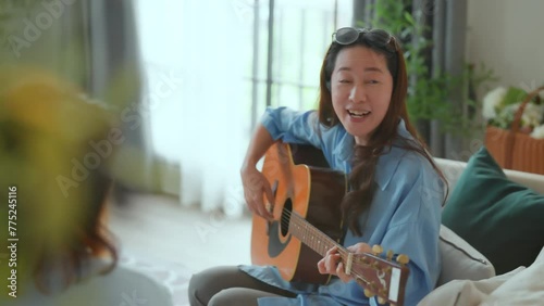 asian adult woman friend gathering having fun together while singing and playing the guitar at home. Friendship, reunion fun party home entertainment and people celebrate festive concept  photo