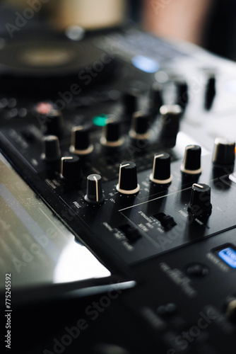A close-up of a DJ mixer with a variety of knobs and buttons