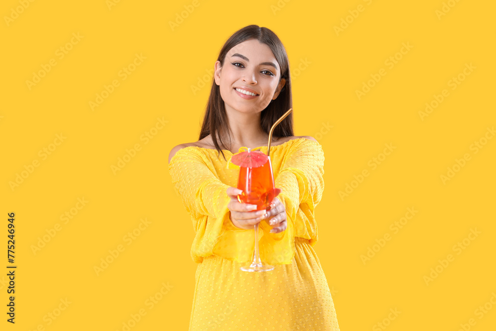 Beautiful young woman with glass of tasty aperol spritz cocktail on yellow background Beautiful young woman with glass of tasty aperol spritz cocktail on yellow background