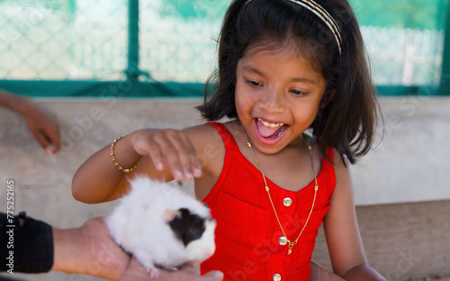 Little girl playing with a guinea pig in a petting zoo sellective focus on girl photo