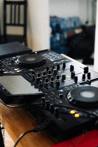 A black DJ controller with two turntables and a mixer on a wooden table