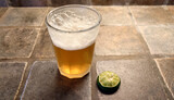 glass of Mexican beer and squeezed lime on a porcelain tiled countertop