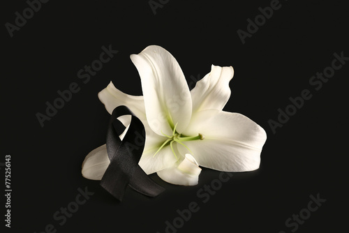 Beautiful lily flower with black funeral ribbon on dark background © Pixel-Shot