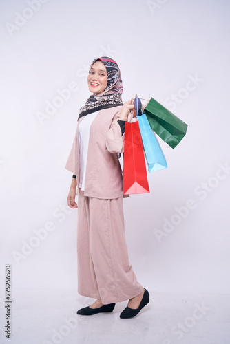 Smiling Asian hijab fashion girl holding shopping bags isolated over white background - shopping, announce, sale, business and lifestyle concept
