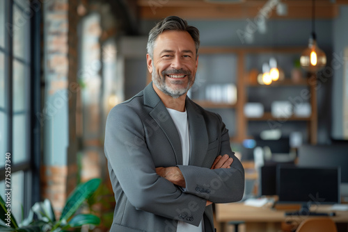 Confident Entrepreneur in Modern Workspace. Smiling middle-aged businessman with arms crossed in office.