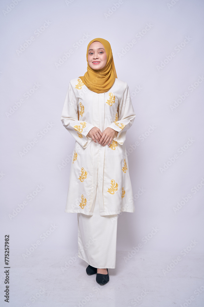 Full length portrait of Asian model wearing modern white batik kebaya with yellow hijab,  isolated over bright background. Stylish Muslim female fashion lifestyle  concept.