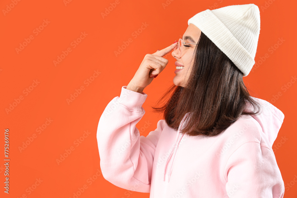 Young woman in eyeglasses on orange background