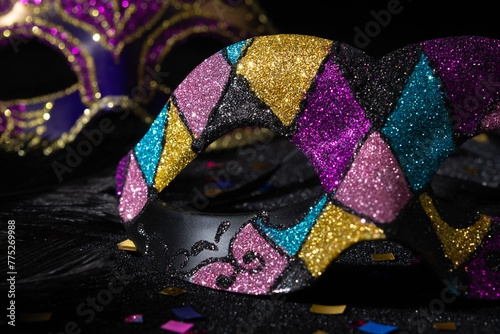 Masquerade mask with glitters and confetties on black background.