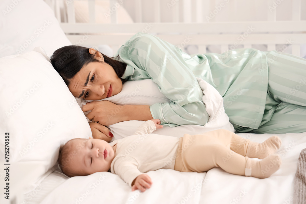 Young woman with her baby suffering from postnatal depression on bed in bedroom Young woman with her baby suffering from postnatal depression on bed in bedroom