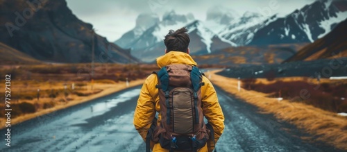 A man in a yellow jacket and backpack walking down a road photo