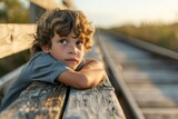 Portrait of a cute little boy sitting on a wooden bridge at sunset