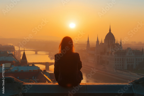 Silhouette of a person admiring a sunset over a cityscape photo