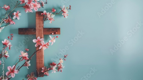 A wooden cross with pink flowers on a blue background. Suitable for religious themes or memorial services