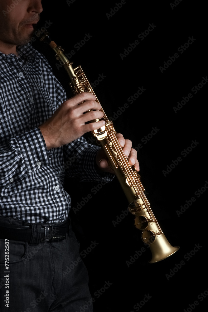 Naklejka premium soprano saxophone in hands on a black background