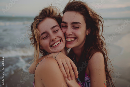 Two women are hugging each other and smiling on the beach