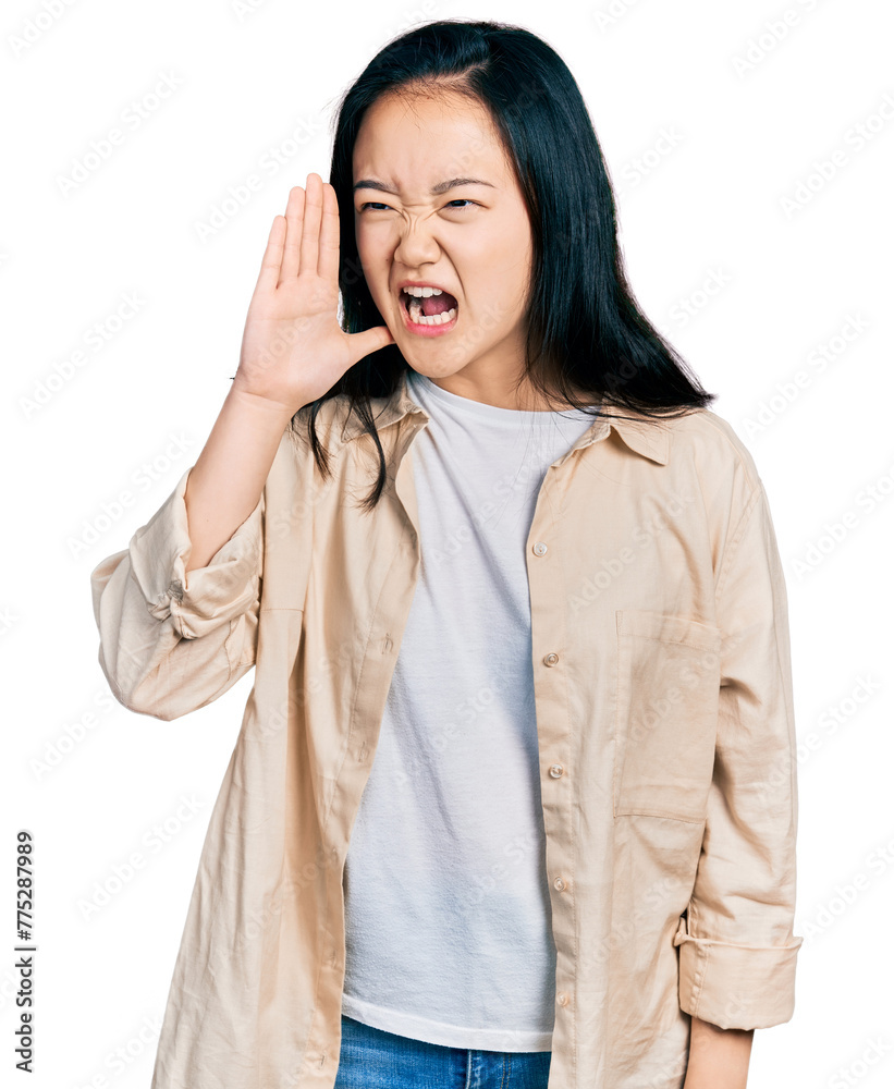 Young chinese woman wearing casual white t shirt and jacket shouting and screaming loud to side with hand on mouth. communication concept. Young chinese woman wearing casual white t shirt and jacket shouting and screaming loud to side with hand on mouth. communication concept.