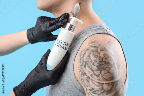 Tattoo master applying crea...