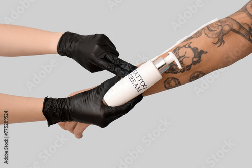 Tattoo master applying crea...
