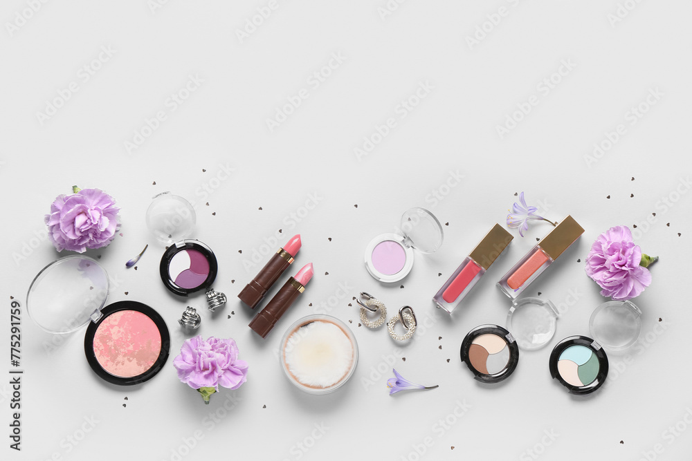 Fototapeta premium Eyeshadows palettes with lipsticks, earrings and flowers on white background