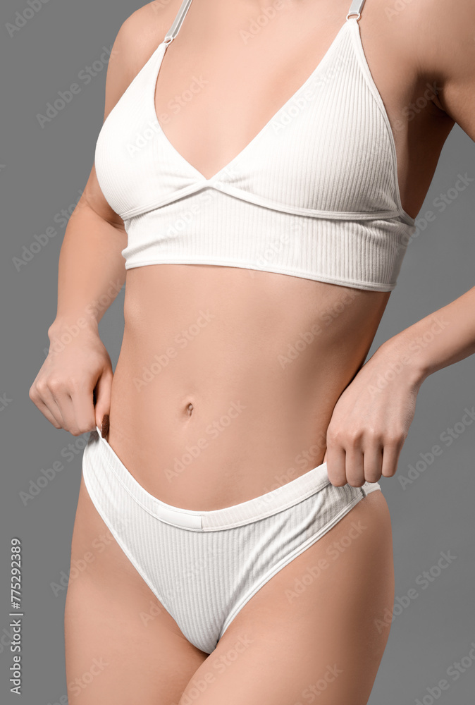 Young woman in white underwear on grey background