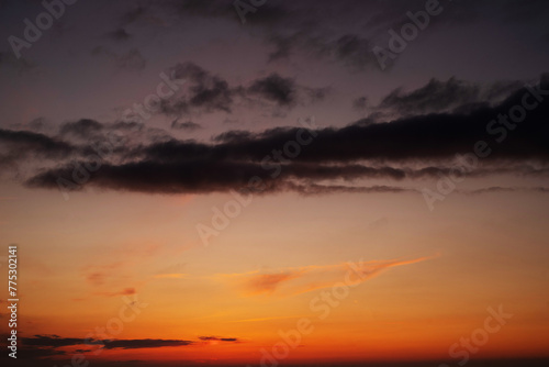 Orange sky background with dark clouds at sunset on a summer evening	