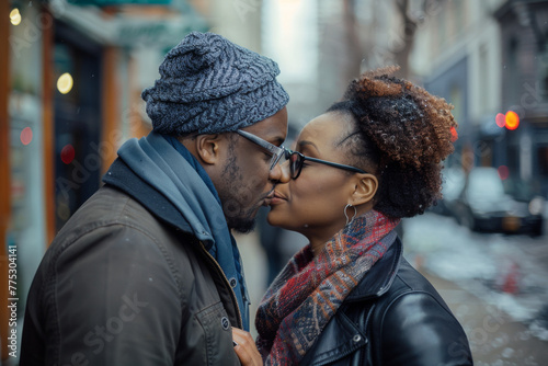 A man kisses a woman on the cheek while wearing glasses