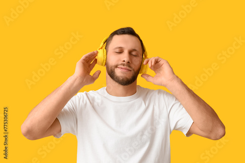 Young man in modern headphones on yellow background © Pixel-Shot