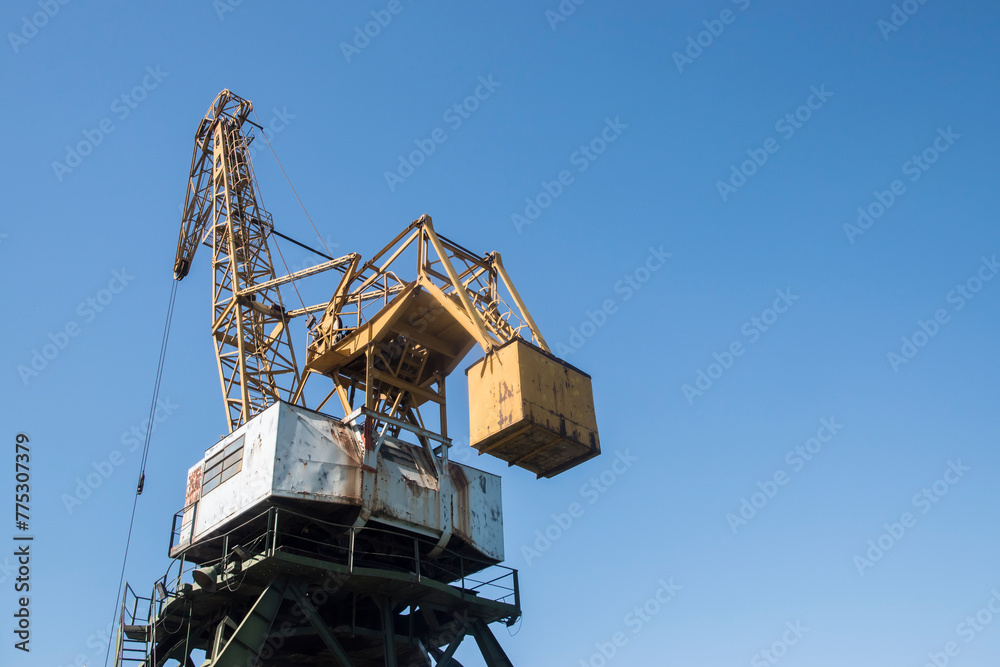 Port industrial cranes at river unloading depot on clear sunny day Port industrial cranes at river unloading depot on clear sunny day