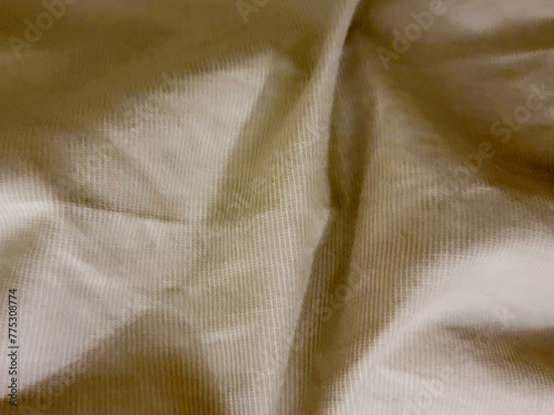 Close-up of a textured cream fabric with soft folds and subtle shadows © Ammar_53