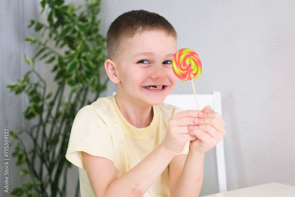 Funny little sweet tooth with sweet lollipop Cute eight year old happy boy with candy in his hand. Happy child eats sweet food. Children's dentist, baby teeth.