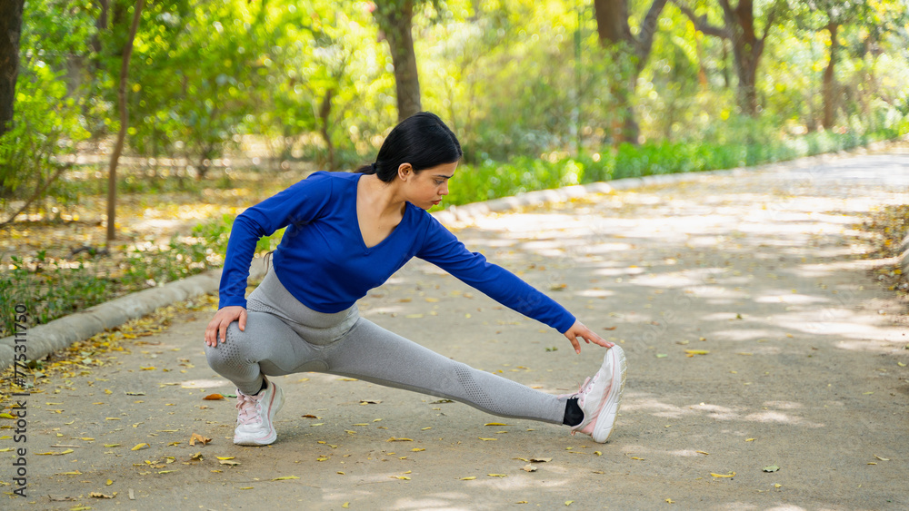 Fototapeta premium Beautiful young woman doing stretches outdoor, stretching exercise, workout and fitness concept