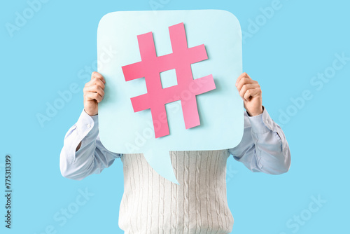 Male office worker holding speech bubble with hashtag on blue background