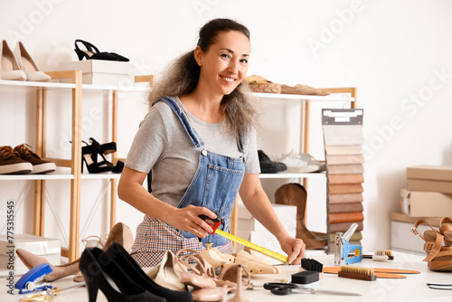 Female shoemaker measuring wooden shoe tree in workshop