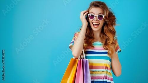 Portrait of an excited beautiful girl wearing dress and sunglasses holding shopping bags isolated over blue background 