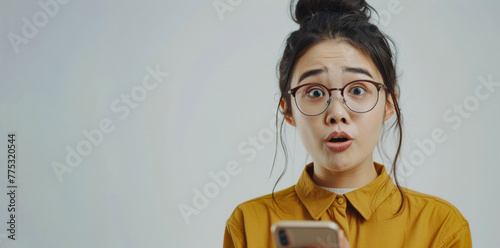 Surprised young woman staring at smartphone in disbelief.